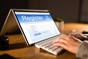 Hands typing on computer with Register on screen